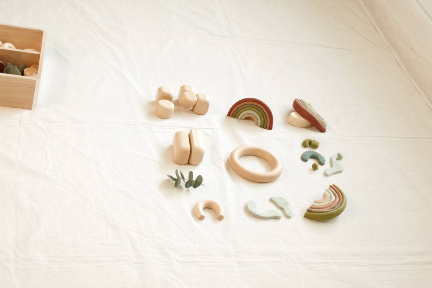 Natural wooden play materials laid out on cream linen