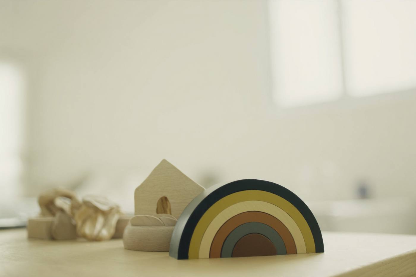 A wooden rainbow stacker and blocks in soft morning light