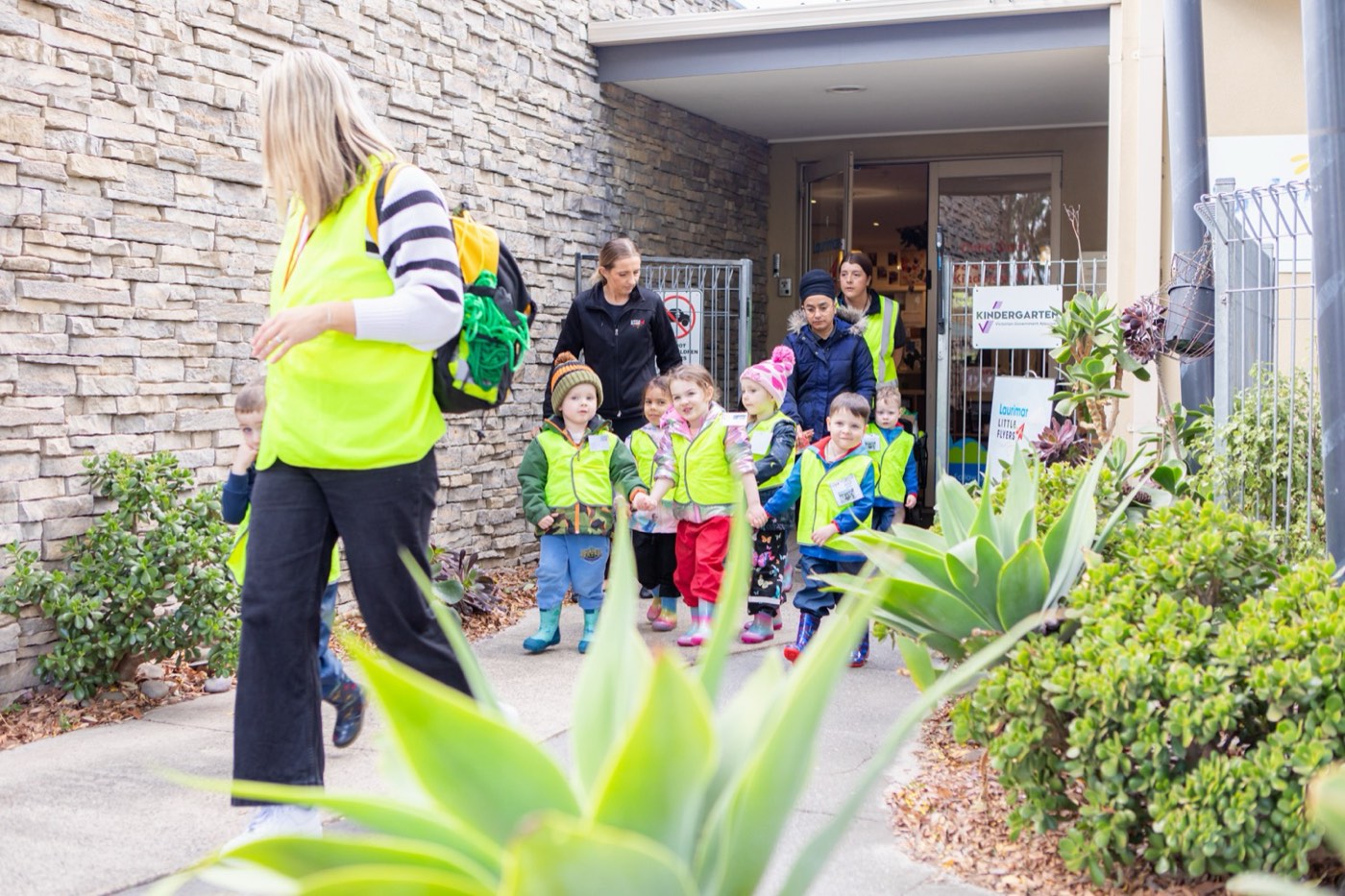 Educators leading children on a local excursion in high-visibility vests