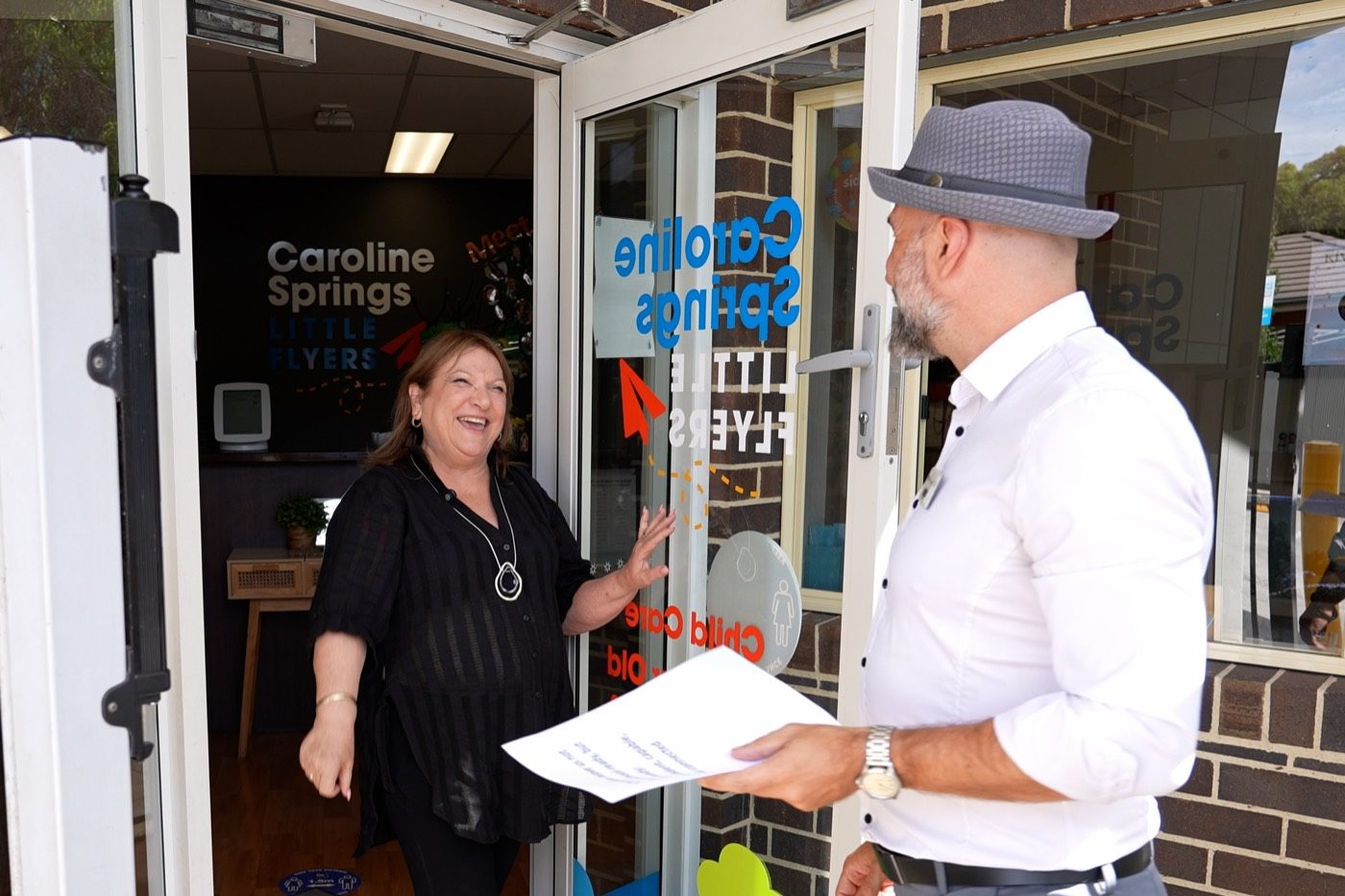 A centre director welcoming a visitor at the entrance of Little Flyers Caroline Springs